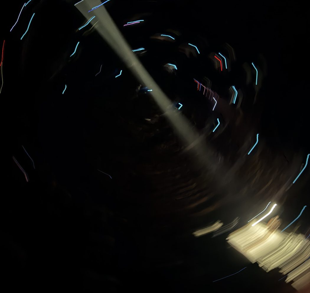 Streaks of light in the dark: a long exposure of a room at night, a beam cutting across it.